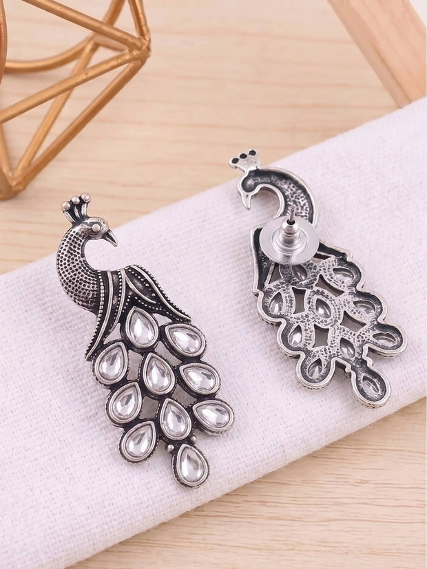 Front and back view of oxidised silver peacock earrings on white fabric showing stud post and hollow reverse