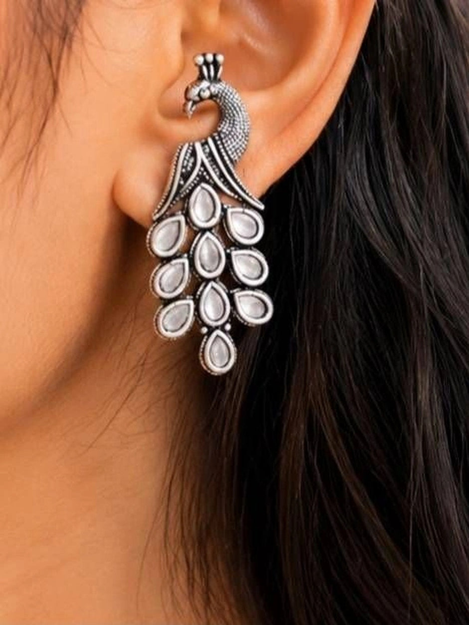 Oxidised silver peacock drop earring worn on ear showing full length and crested peacock head detail