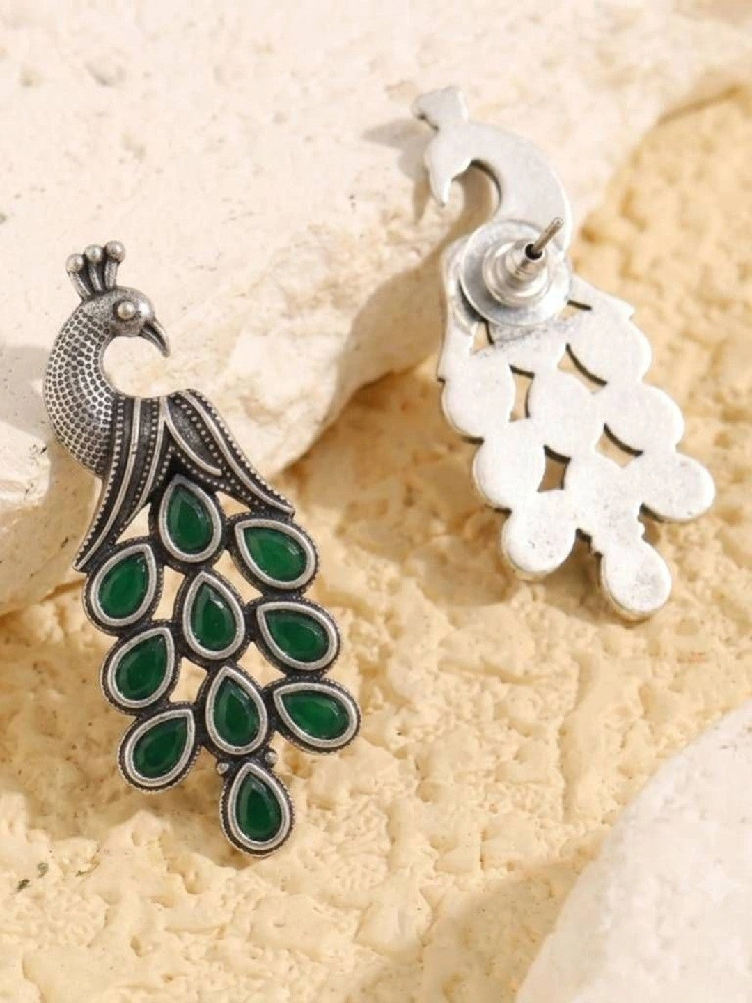 Front and back view of oxidised silver peacock earrings showing push-back stud fastening on stone surface