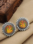 Two oxidised silver Ganesha stud earrings resting on cream fabric beside a carved wooden box