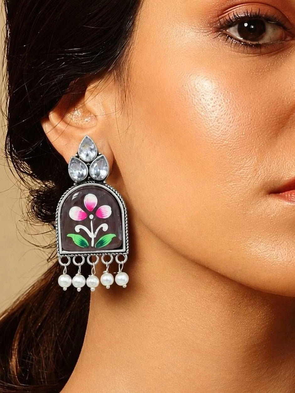 Oxidised silver floral jhumka earring worn on a woman's ear, showing crystal top and pearl drops