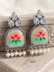 Pair of oxidised silver chandbali earrings propped against rustic wood with a loose crystal stone nearby