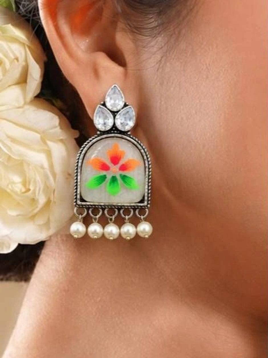 Model wearing one meenakari chandbali earring with white roses in the background showing scale and fit