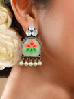 Model wearing one meenakari chandbali earring with white roses in the background showing scale and fit