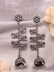 Pair of oxidised silver bird jhumka earrings laid flat on white fabric showing front detail of both pieces