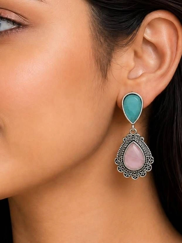 Woman wearing oxidised silver teardrop drop earring with teal stud top and pink stone pendant