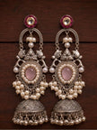 Pair of oxidised silver teardrop jhumka earrings laid flat on dark wooden surface