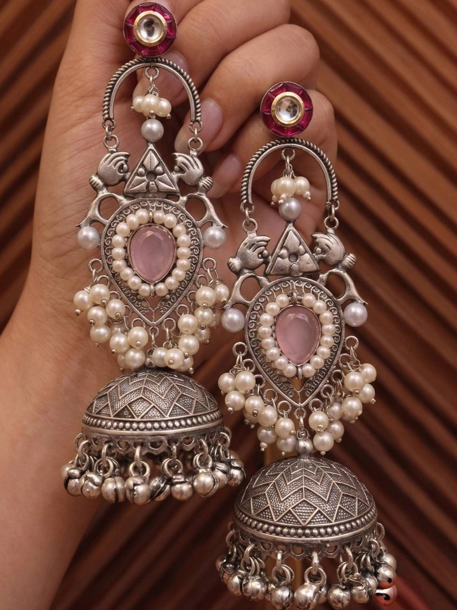 Both oxidised silver jhumka earrings held in hand showing front and side detail