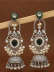 Two oxidised silver jhumka earrings with pearl-bordered teardrop stone hanging from a wooden rod