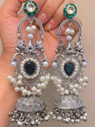 Close-up of a pair of oxidised silver pearl chandbali jhumka earrings held in a woman's palm