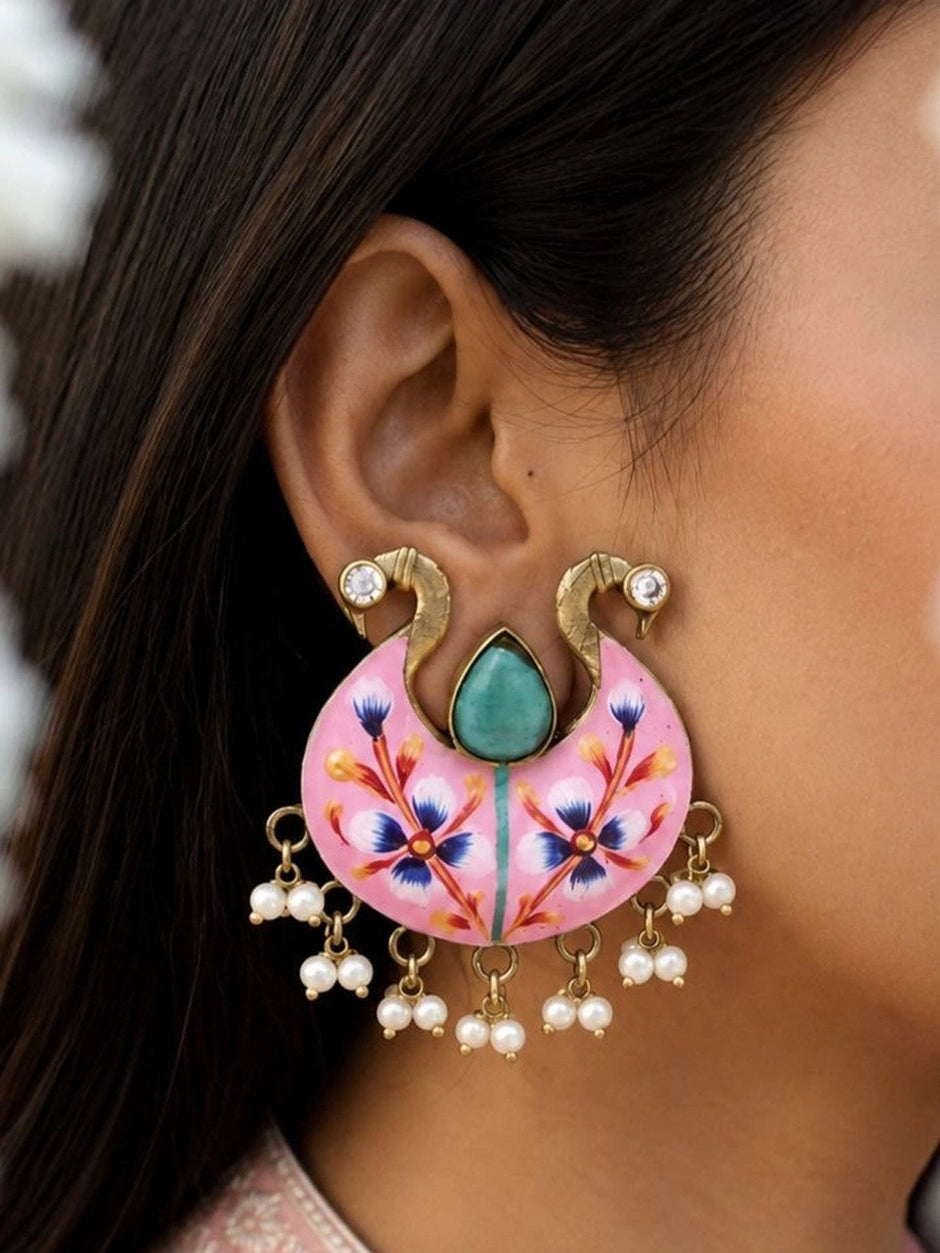 Pink meenakari chandbali earring worn on ear, showing swan motifs and pearl drops