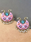 Pair of pink meenakari chandbali earrings laid flat on grey and beige surface