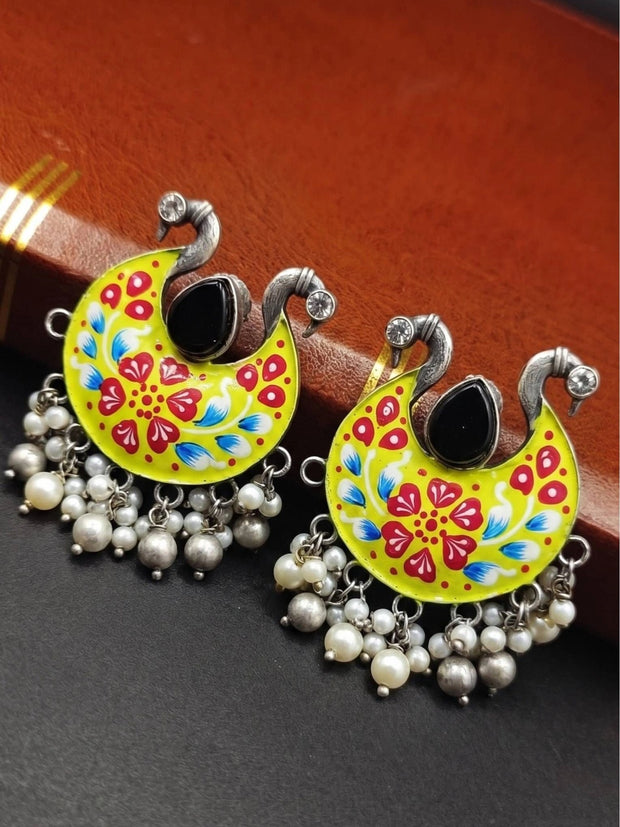 Pair of yellow meenakari chandbali earrings with red floral enamel and pearl bead fringe on dark surface