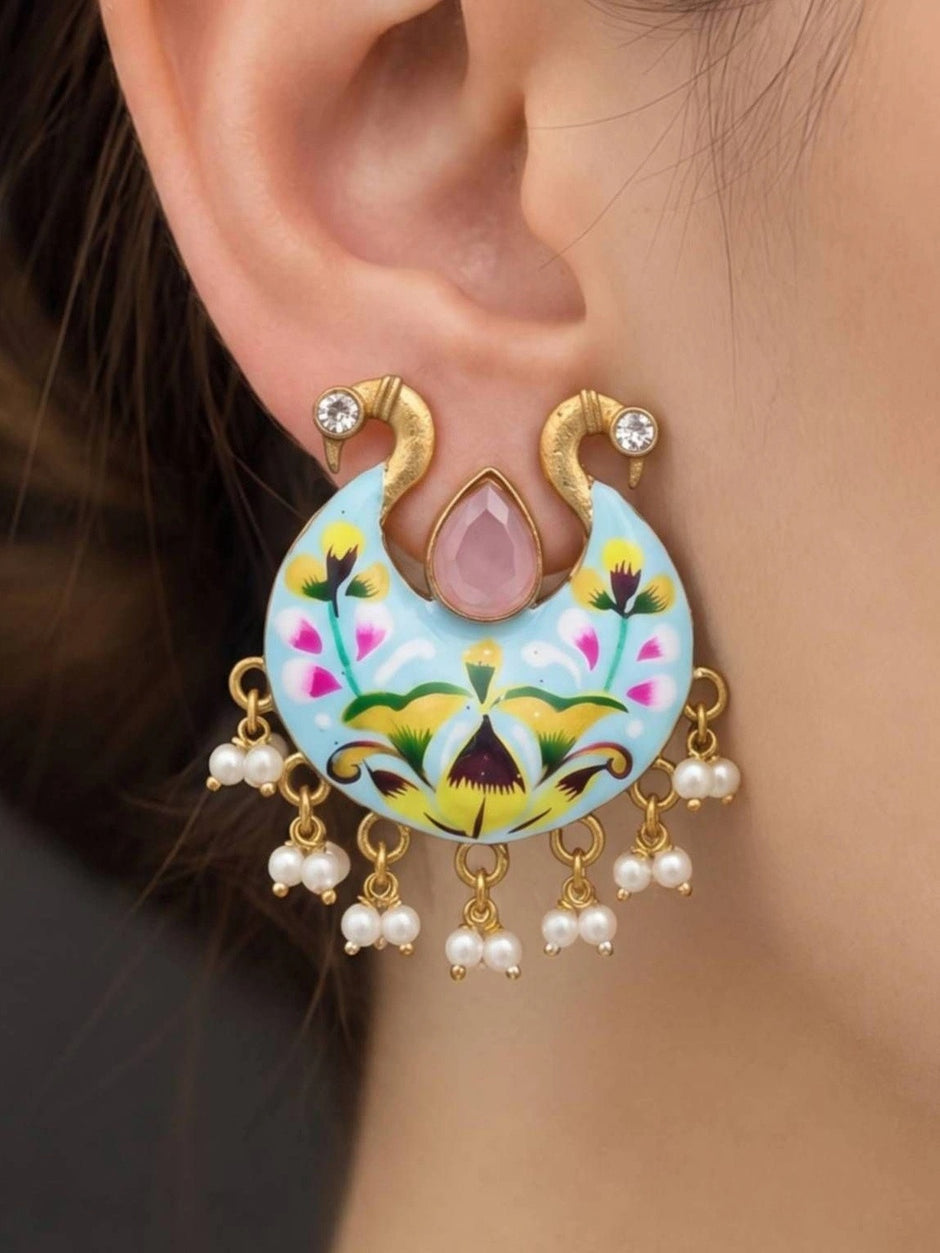 Close-up of hand-painted peacock chandbali earring worn on a woman's ear