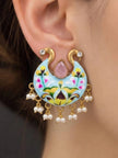 Close-up of hand-painted peacock chandbali earring worn on a woman's ear