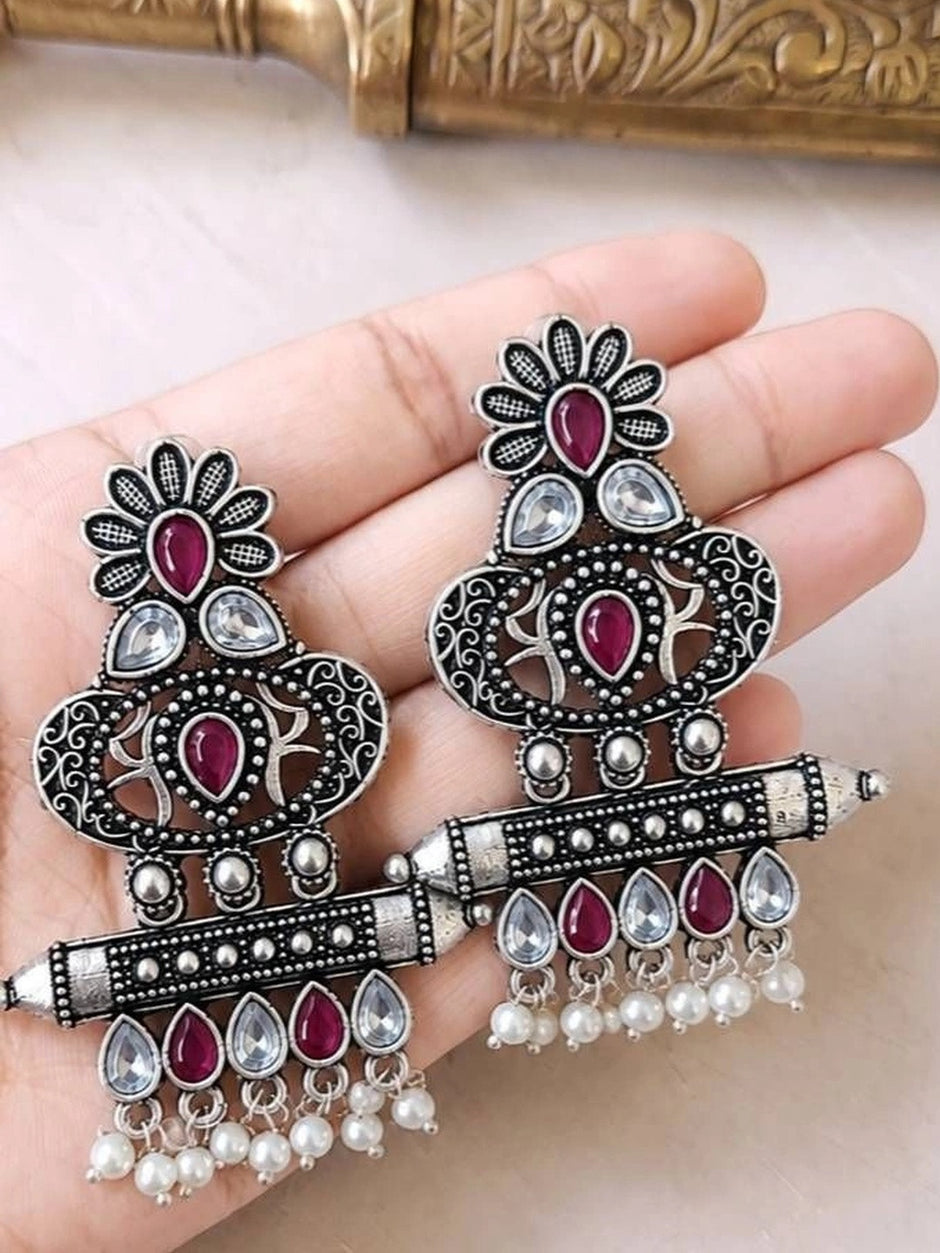 Both oxidised silver chandbali earrings held in an open palm showing full design and pearl drop fringe