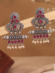Two oxidised silver chandbali earrings balanced on wooden prop against warm beige background