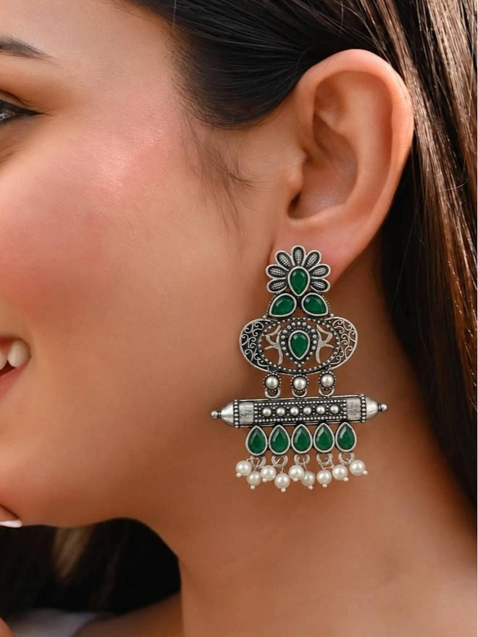 Hand holding large oxidised silver chandbali earring beside smaller one to show scale and detail
