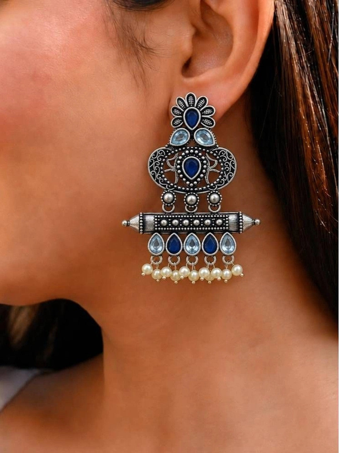 Oxidised silver chandbali earring worn on ear showing blue stone and pearl drop detail