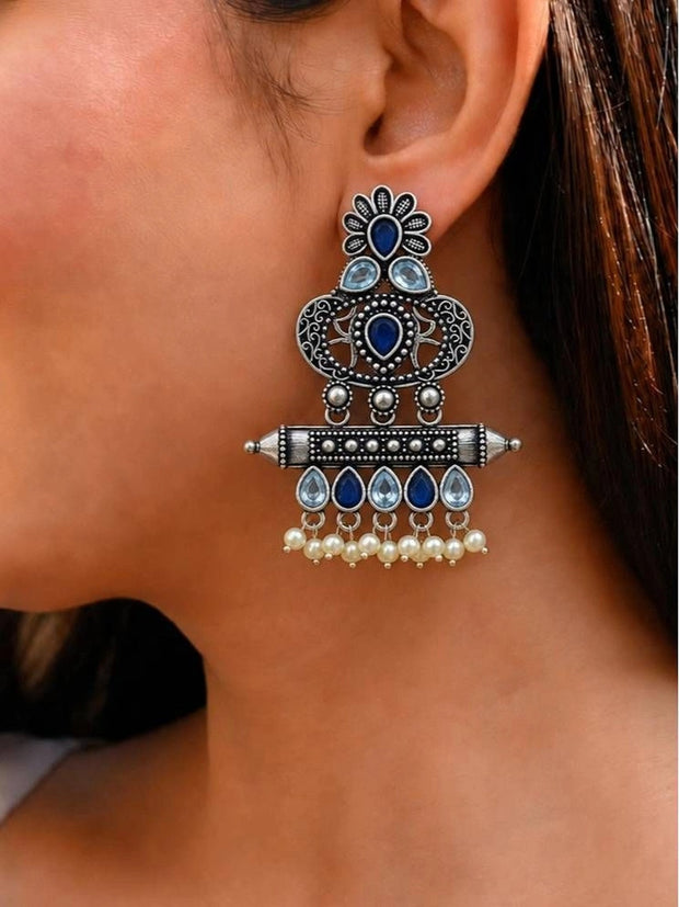 Oxidised silver chandbali earring worn on ear showing blue stone and pearl drop detail