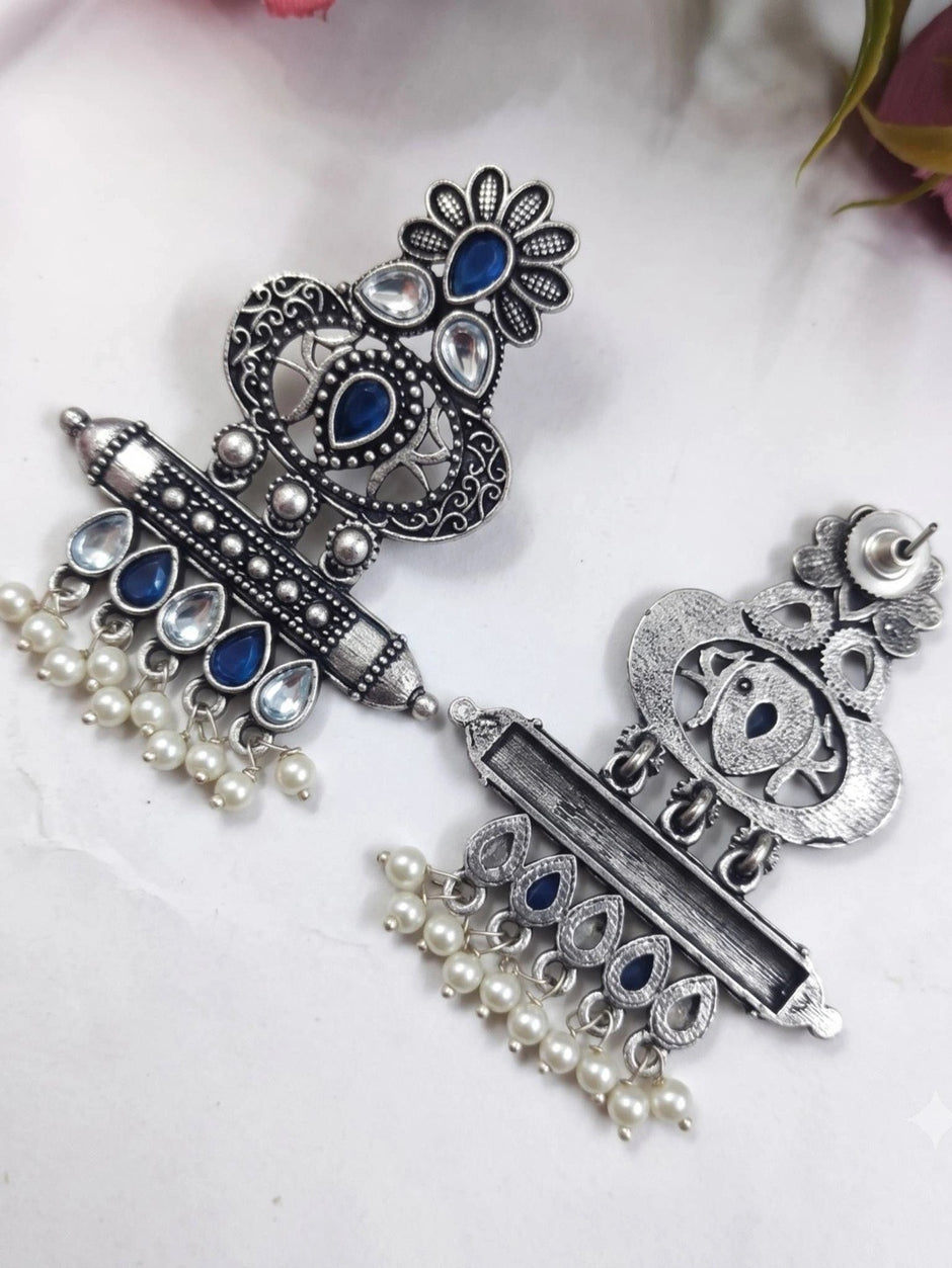 Front and back view of oxidised silver chandbali earrings laid flat on white surface
