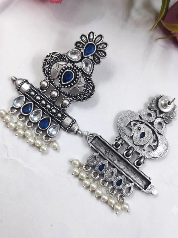 Front and back view of oxidised silver chandbali earrings laid flat on white surface