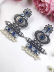 Pair of oxidised chandbali earrings with blue teardrop stones and white pearl danglers on white surface