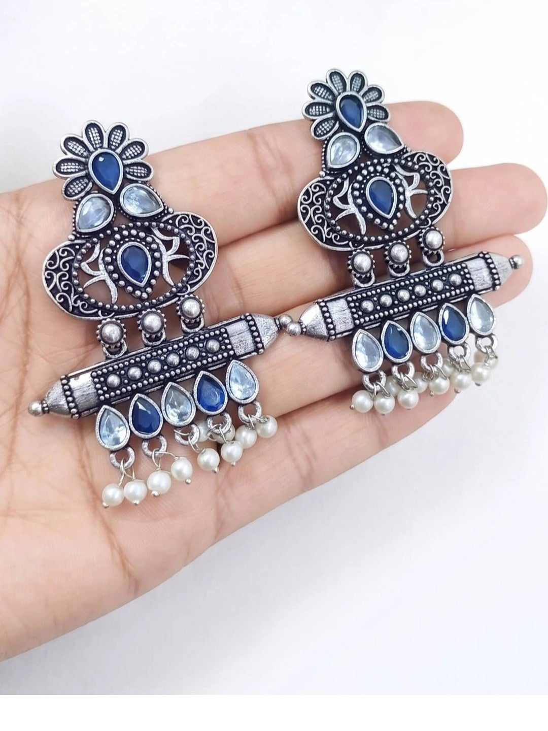 Both oxidised silver chandbali earrings held in open palm showing full size and design