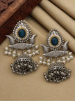 Pair of oxidised silver jhumka earrings laid flat showing teal cabochon, seed pearl frame and silver ghungroo detailing