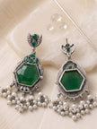 Front and back view of oxidised silver green stone chandbali earrings laid flat on white surface