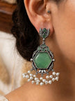 Oxidised silver hexagon green stone drop earring worn on a woman's ear with pearl fringe