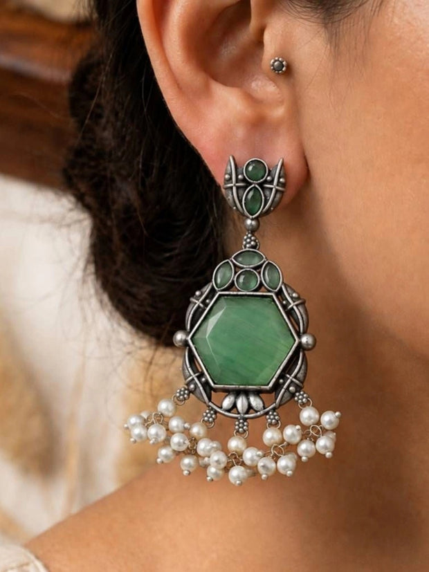 Oxidised silver hexagon green stone drop earring worn on a woman's ear with pearl fringe