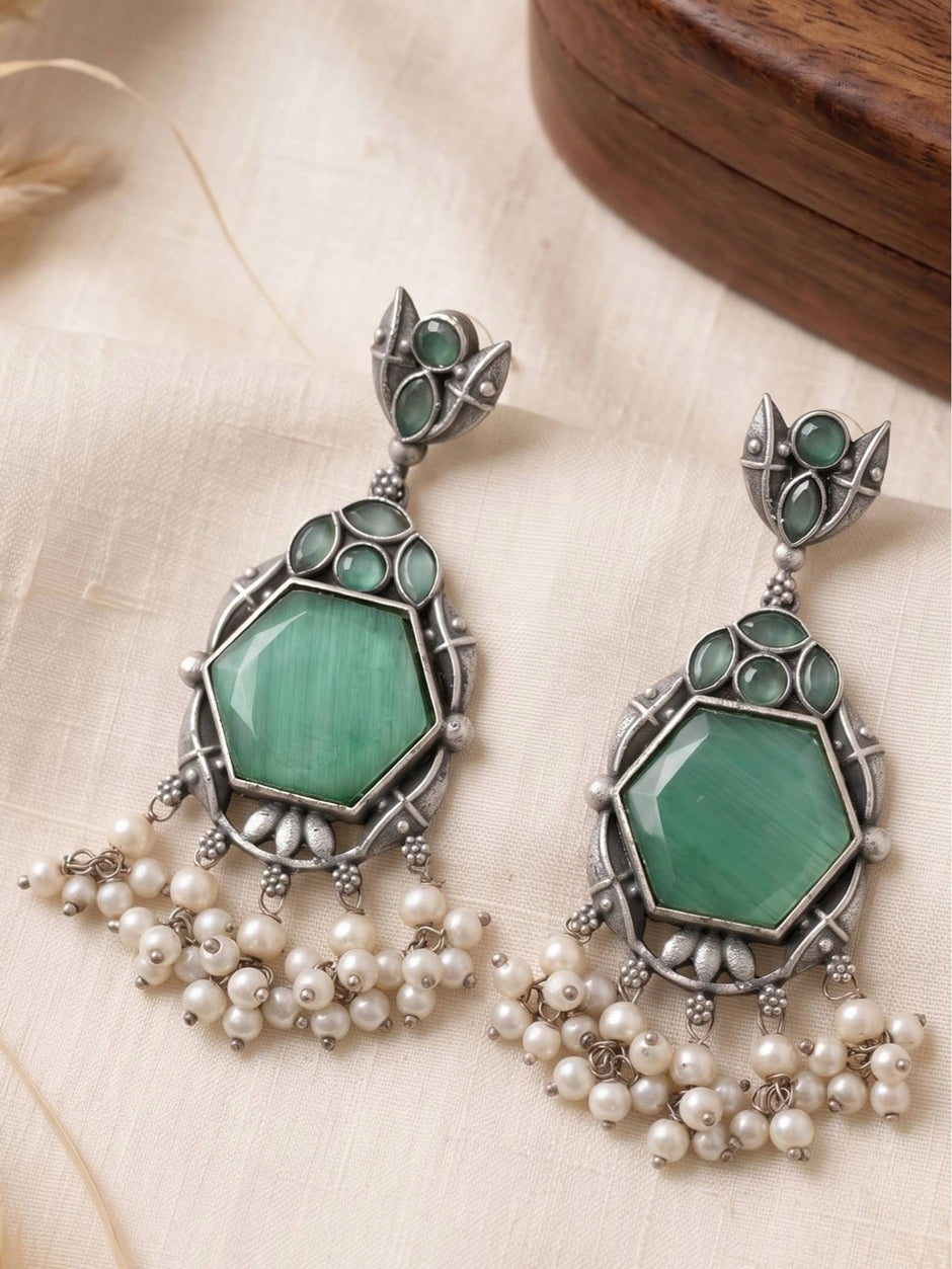 Both earrings showing oxidised silver frame green hexagon stone and cascading white pearl fringe