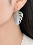 Oxidised silver monstera leaf drop earring worn on a woman's ear against dark hair and white top