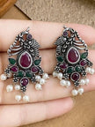 Pair of oxidised silver peacock earrings with pearl drops held in an open palm