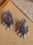 Two oxidised silver peacock drop earrings laid flat showing front design with stones