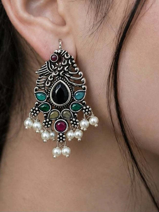 Oxidised silver peacock chandbali earring worn on ear showing multicolour stones and white pearl drops