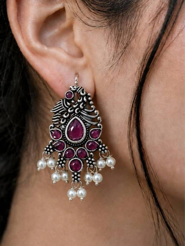Oxidised silver peacock chandbali earring worn on ear with fuchsia stones and pearl drops