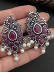 Two oxidised silver peacock earrings held in palm showing scale and full design