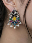 Oxidised silver peacock drop earring worn on a woman's ear, showing multicolour stones and white pearl drops