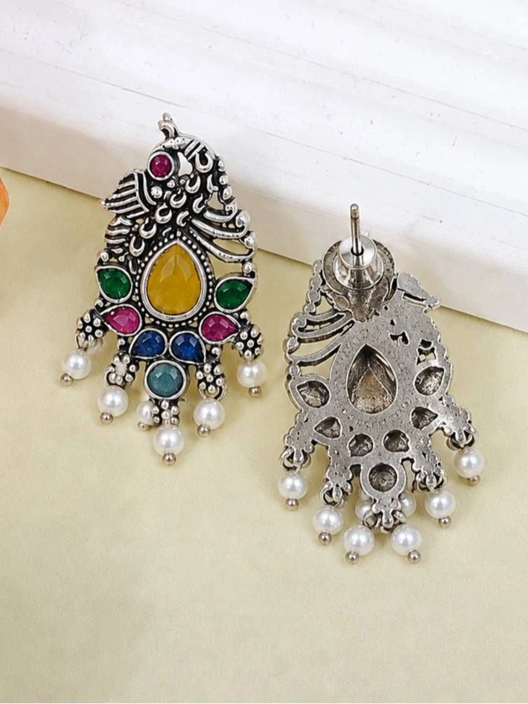 Front and reverse of oxidised silver peacock earring showing push-back stud fitting and hollow cast back