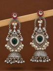 Side-by-side pair of oxidised silver chandbali jhumka earrings showing peacock motif, green stone, pearl clusters and ghungroo drops against brown background