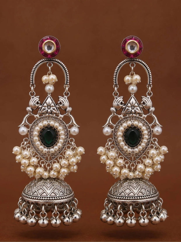 Front-facing pair of oxidised silver jhumka earrings with pink kundan tops, arched chand frame and domed ghungroo-fringed bell on brown background