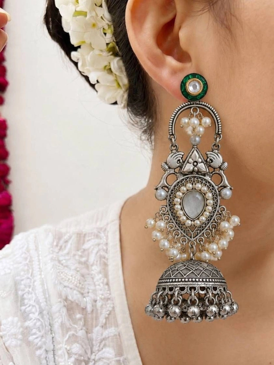 Close-up of oxidised silver jhumka earring worn, showing pearl clusters, filigree teardrop, and domed bell drop