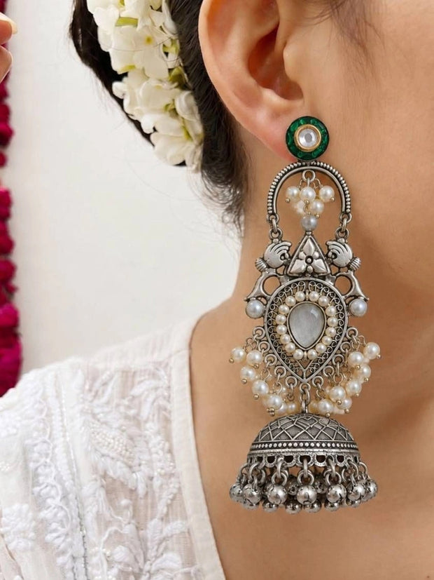 Close-up of oxidised silver jhumka earring worn, showing pearl clusters, filigree teardrop, and domed bell drop