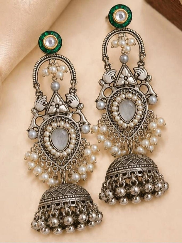 Pair of oxidised silver pearl jhumka earrings laid flat on cream fabric, front and side view