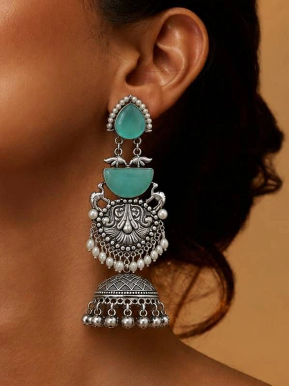 Oxidised silver turquoise jhumka earring worn on ear showing full tiered length with ghungroo drops