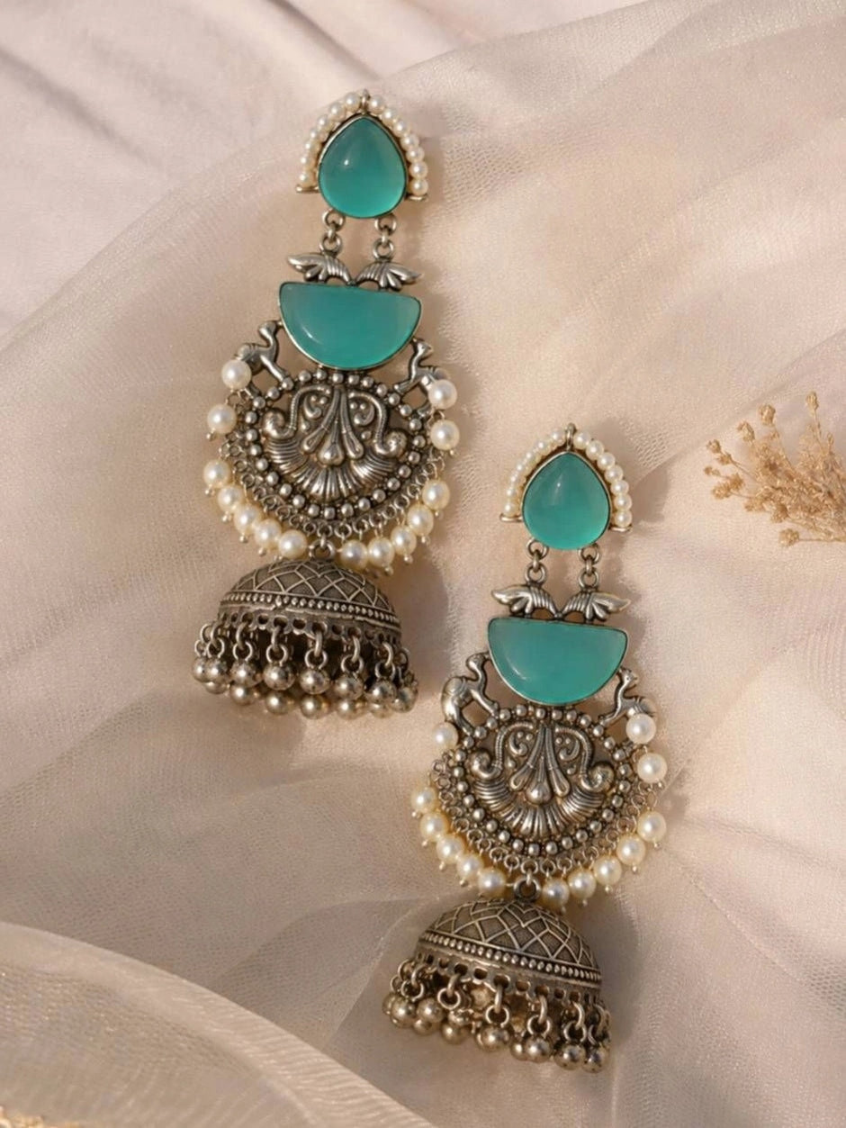 Pair of oxidised silver jhumka earrings laid flat on ivory fabric showing front detail and pearl fringe