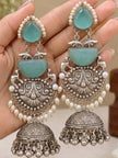 Two oxidised silver turquoise jhumka earrings held in palm showing repousse scrollwork and pearl bead drops