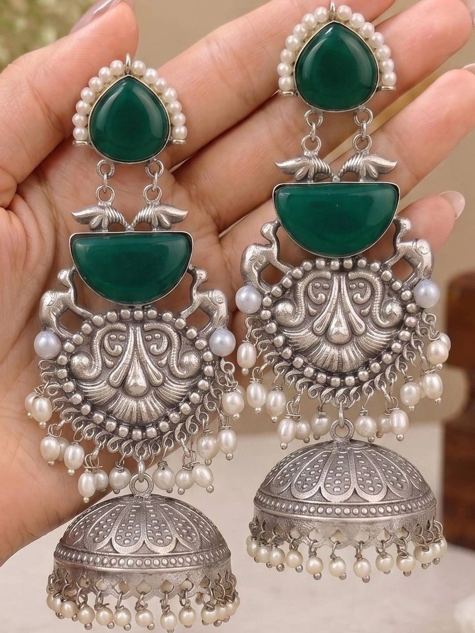 Both jhumka earrings held in open palm showing full three-tier design with dome bell and pearl drops